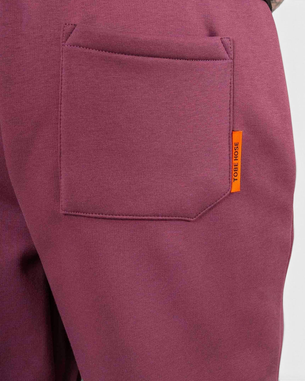 Tobe Hose Studio Herrenhose in Pflaume mit Gesäßtasche und orangefarbenem Markenlabel