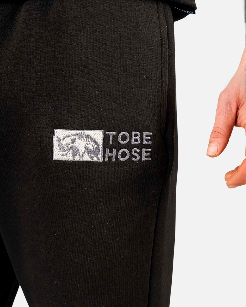 Tobe Hose Studio Herrenhose in Schwarz mit gesticktem Hyänen-Logo und Reißverschlusstasche