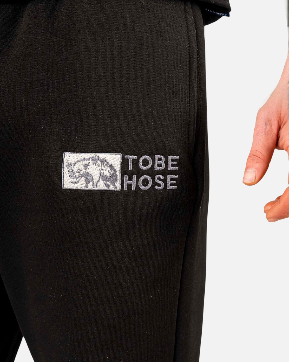 Tobe Hose Studio Herrenhose in Schwarz mit gesticktem Hyänen-Logo und Reißverschlusstasche