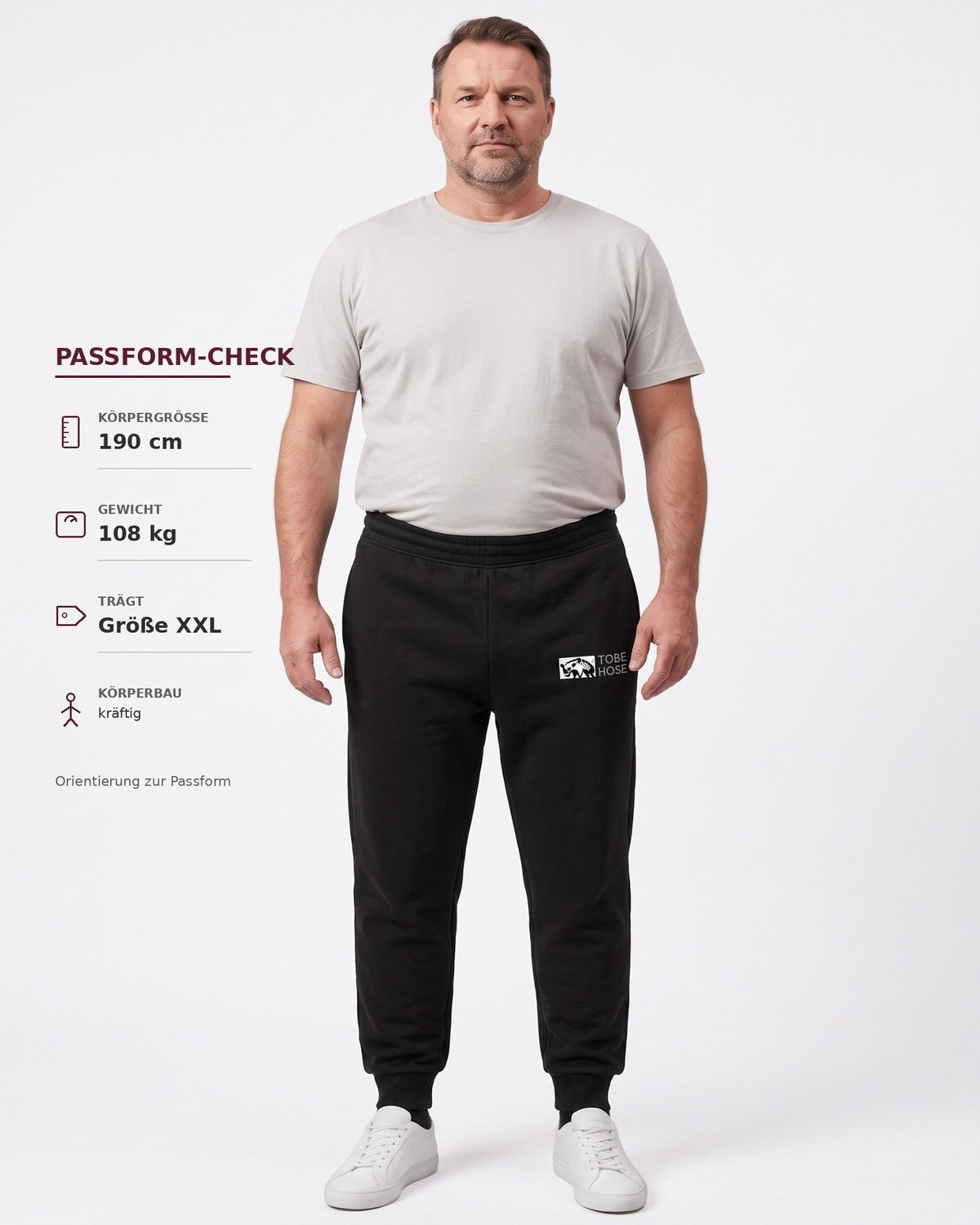 Ein Mann trägt eine schwarze Tobe Hose Studio Jogginghose mit Hyänen-Logo und Bündchen an einem hellen Hintergrund.
