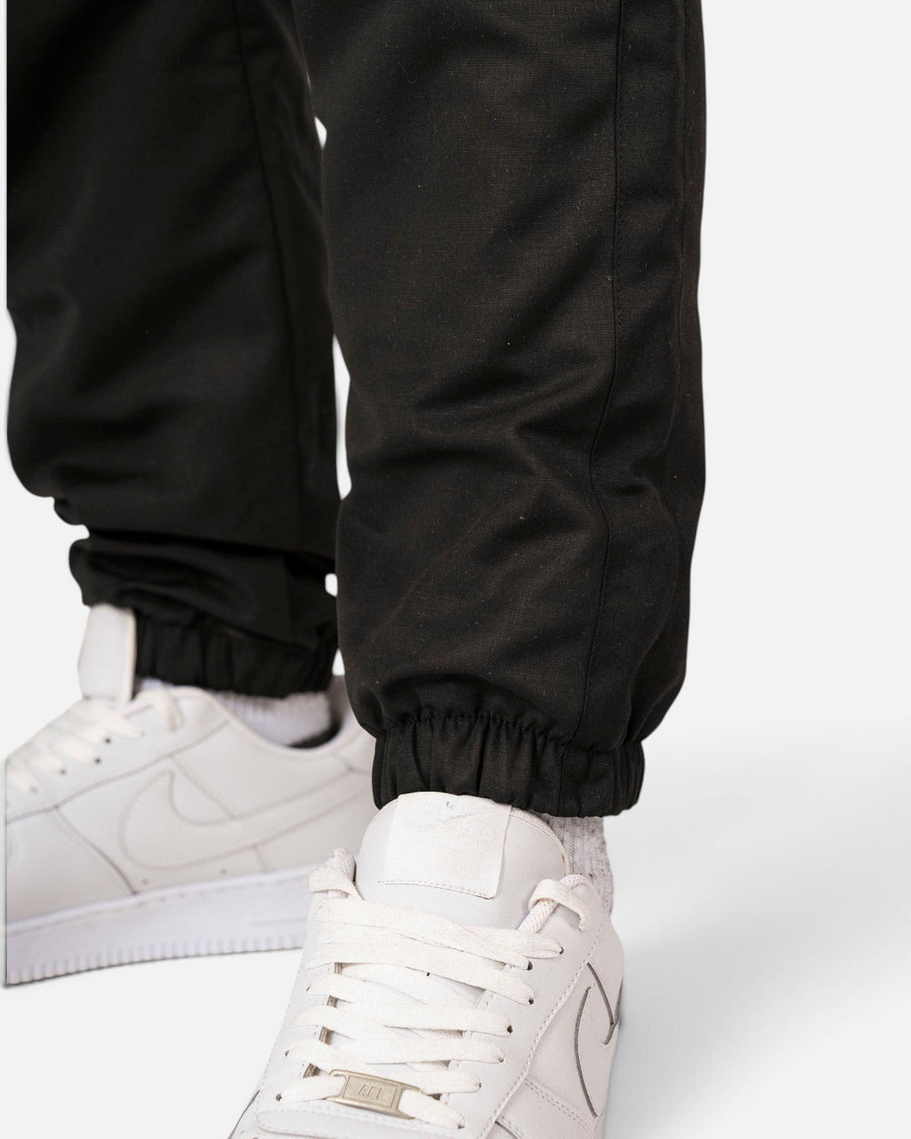 Tobe Hose Studio Luft Herrenhose in Schwarz aus robustem Nylon mit elastischem Beinabschluss und weißem Sneaker