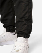 Tobe Hose Studio Luft Herrenhose in Schwarz aus robustem Nylon mit elastischem Beinabschluss und weißem Sneaker