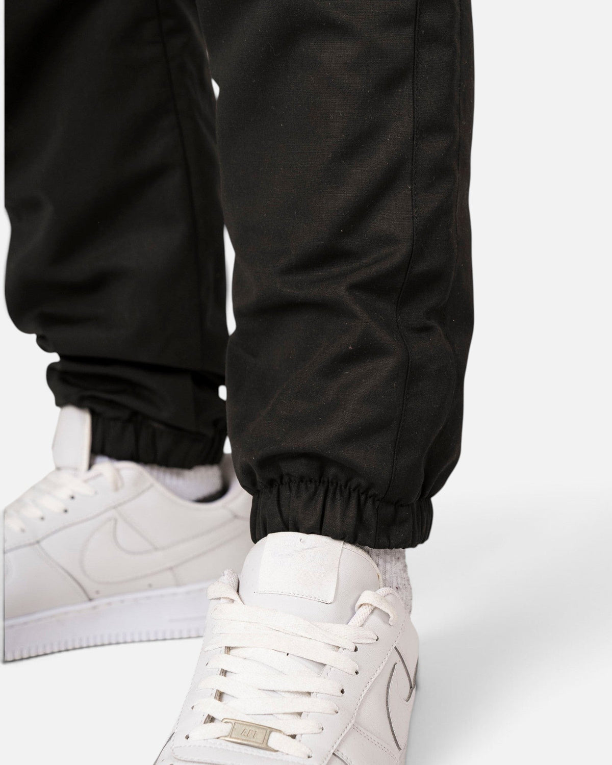 Tobe Hose Studio Luft Herrenhose in Schwarz aus robustem Nylon mit elastischem Beinabschluss und weißem Sneaker