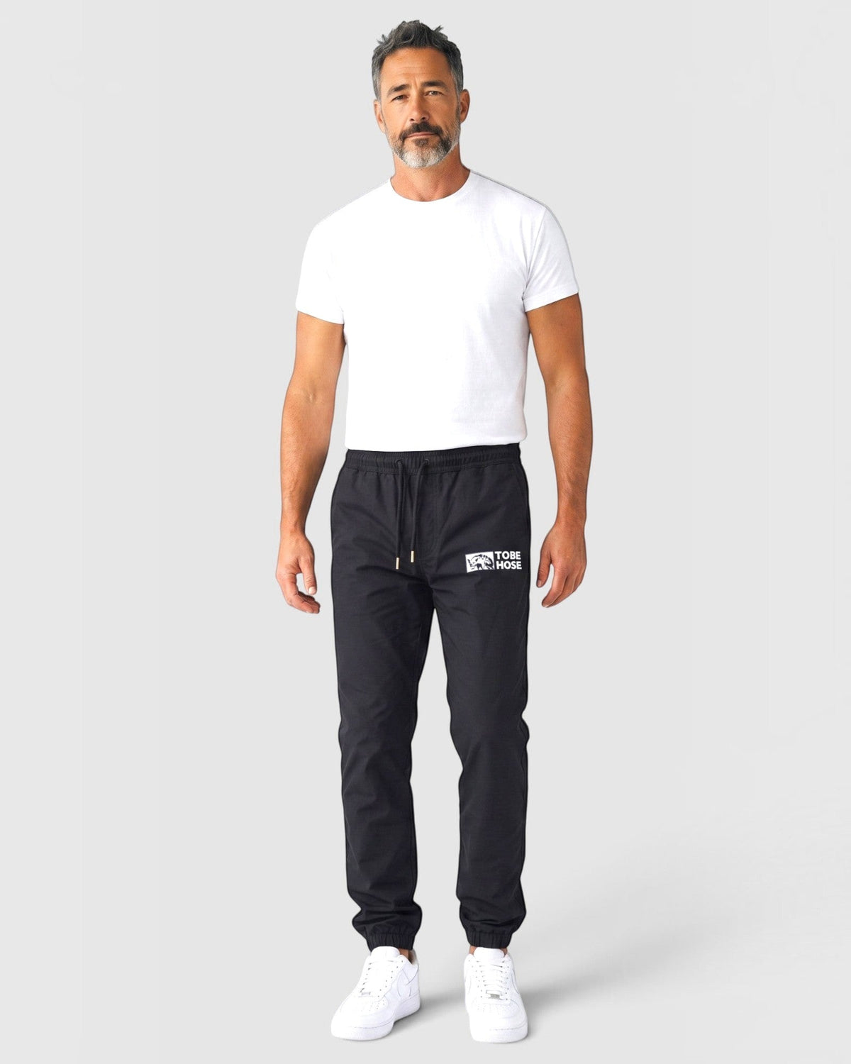 Tobe Hose Studio Luft Herrenhose in Schwarz aus robustem Nylon mit gesticktem Hyänen-Logo und Reißverschlusstaschen
