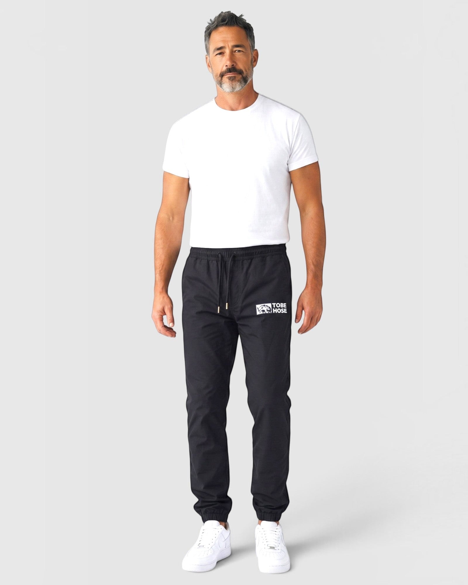 Tobe Hose Studio Luft Herrenhose in Schwarz aus robustem Nylon mit gesticktem Hyänen-Logo und Reißverschlusstaschen