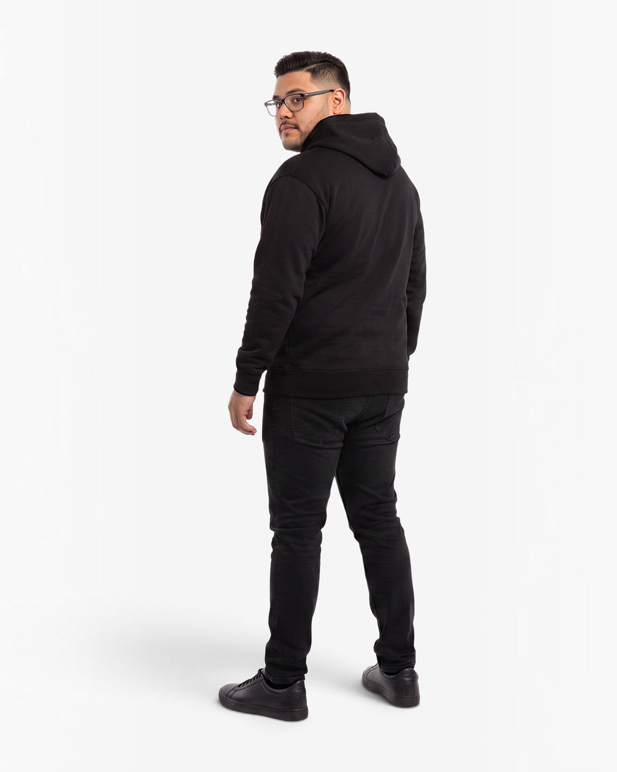 Ein Mann trägt den schwarzen Tobe Hose Studio Zip-Hoodie Fels von hinten mit Kapuze und schlichter Passform.
